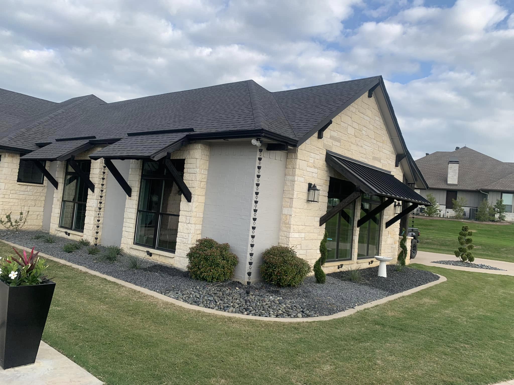 Modern residential home with gravel garden beds, topiaries, and manicured lawn