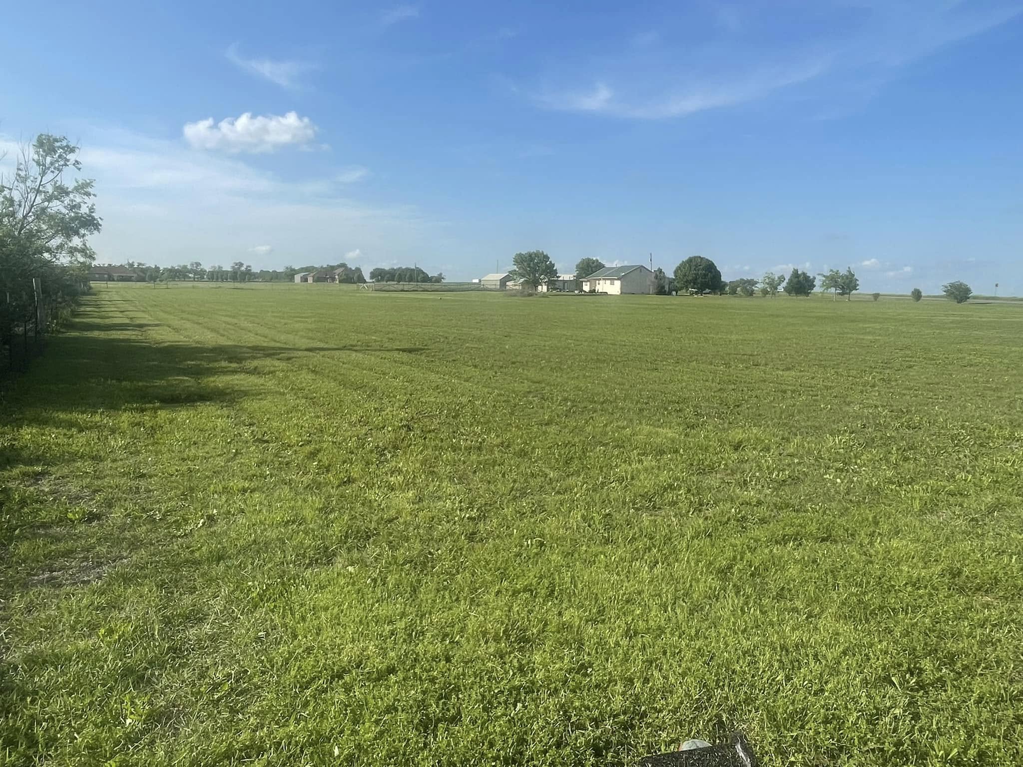 Wide expanse of freshly mowed green lawn under a clear blue sky